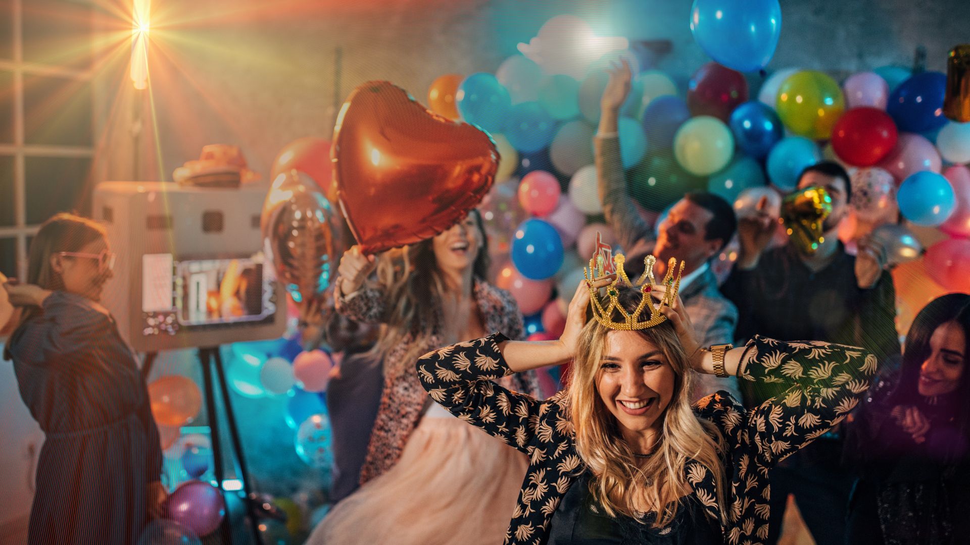 A woman wearing a crown standing in front of balloons