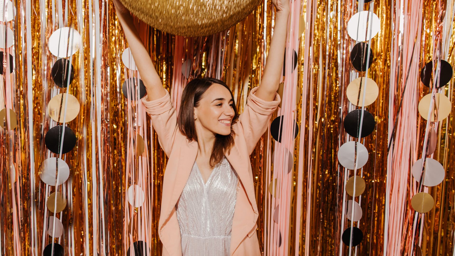 A woman standing in front of a backdrop of gold and black confetti