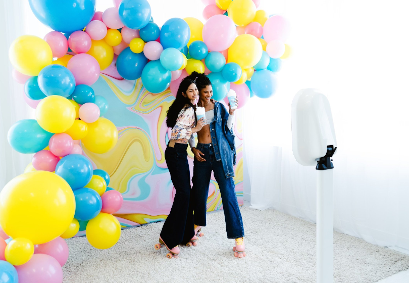 Two women standing in front of a wall of balloons